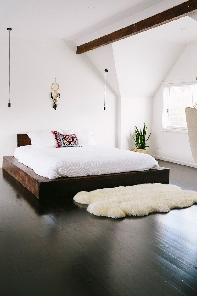 The timber bed frame is the highlight of this room. It adds rustic charm into this otherwise contemporary bedroom. The rug invites warmth into this large space.