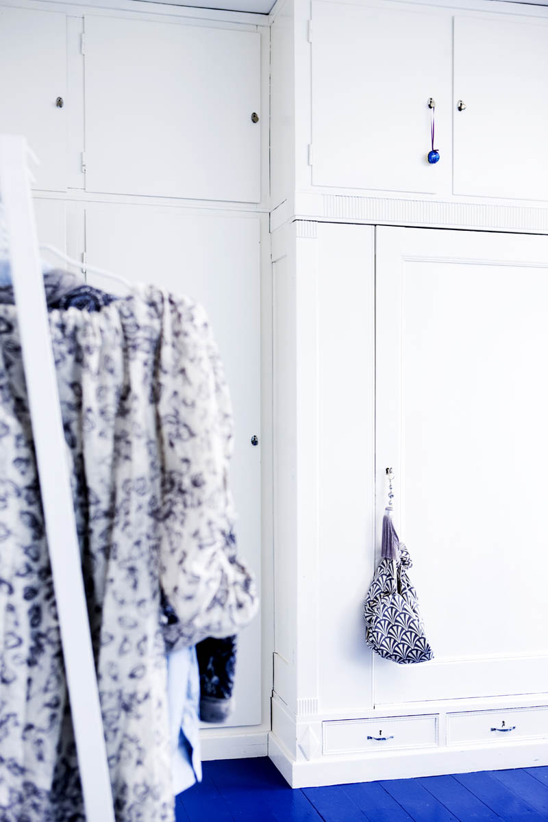 painted white wardrobes and a bright blue painted floor